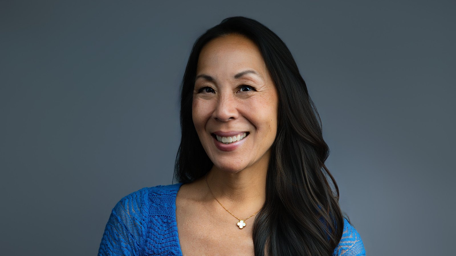 Dr. Erica Song, founder of Vibrant Life Medicine, smiling in a blue top against a grey background.
